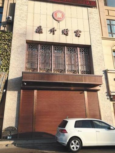 12月10日，位于长春市临河街中海紫御华府的一栋门面楼的正中央，挂着“鼎升财富”四字以及一个商标，商标下的卷帘门紧锁。